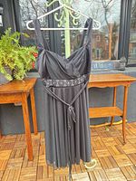 Front view of black cocktail dress on hanger