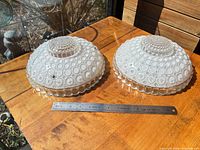 Pair of glass hobnail ceiling light shades top view beside ruler