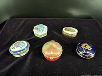Five trinket boxes grouped on black fabric