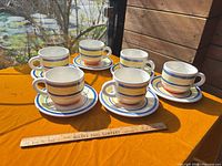 Full set of six striped cups and saucers with ruler for scale