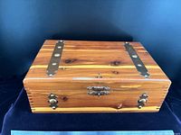 Closed cedar box front view showing brass-tone straps, latch, and wood grain