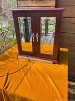 Front view of closed jewelry box showing mirrored doors and wood veneer finish