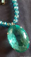 Close-up of large oval aquamarine crystal pendant and adjacent beads