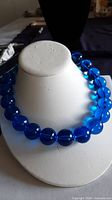 Necklace on display bust showing full strand of large translucent blue beads