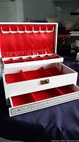 Jewellery case open showing tiered red velvet interior and hooks