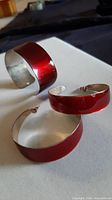 Cuff bracelet and both earrings showing red lacquer and interior metal