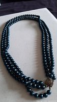 three-strand blue faux pearl necklace laid flat highlighting clasp