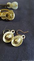 Close-up of cowboy hat earrings and gold acoustic guitar brooch