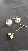 full set: two cufflinks and tie tack on dark cloth