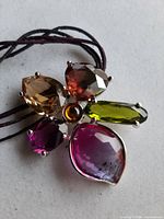 Front view of pendant showing five coloured crystals and center stone on cord