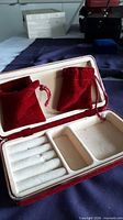 Open jewellery case showing interior compartments and two red velvet pouches