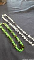Both necklaces laid out: clear crystal and green/yellow beads