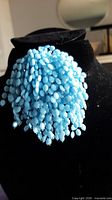 Front view showing dense cluster of light blue beads