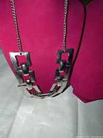 Front view of necklace on display bust showing geometric rectangular links and chain.