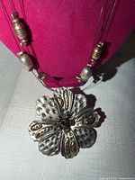 Necklace close-up showing charms and flower pendant detail