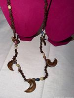 Full view of necklace laid on display bust showing wooden chip beads, stone rounds and curved wooden pendants