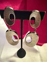 Front view of both earrings on stand showing overall design and condition