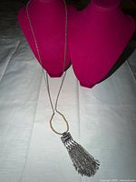 Full view of necklace draped on busts showing overall length and tassel