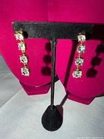 Front view of both earrings on stand showing four clear stones each