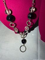 Close view of necklace on display bust showing black stones, clear beads, metal rings and pendant