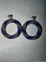 Front view of both intertwined blue and gray beaded hoop earrings with stud posts