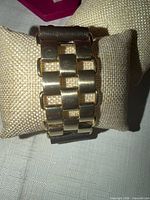 Front view showing goldtone metal link panel on brown leather cuff