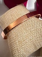 Copper cuff bracelet on display pillow showing polished surface
