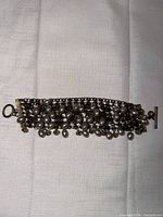 Full view of wide chain-mail bracelet laid flat showing toggle clasp and bead arrangement