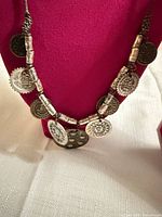 Front view of necklace showing nine coin pendants and tubular beads