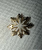 Front view of gold snowflake brooch with diamond accents