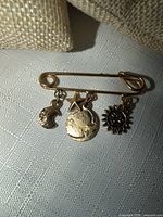 Front view of gold-tone brooch showing all four charms