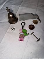 All items laid out including bell tape measure, keychains, die, cufflink