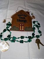 Entire lot laid out: plaque, bead necklace, shell pendant, keys, charms