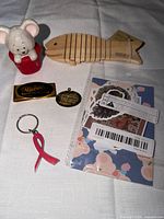 All items laid out: ceramic mouse, wooden fish, money clip, pendant, keychain, sticker pack