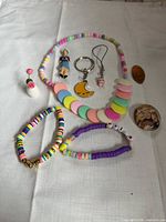 All items laid out on cloth showing necklace, bracelets, charms, vase, penny, button
