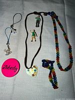 Entire lot laid out showing necklace, badge, phone charms, beaded necklace and bracelet