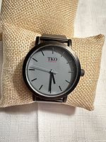 Front view of watch on cushion showing dial, case, and brand name