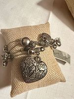 Bracelet displayed on pillow showing layered chains and large heart charm