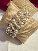 Front angled view of the multi-row pearl and silver-tone bead stretch bracelet on display pillow