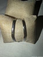 Front view of silver-tone double-band cuff bracelet on display cushion