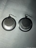 Front view of both earrings showing layered gunmetal and silver-tone discs