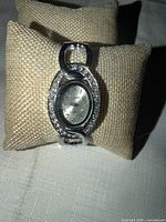Front view of silver-tone Geneva watch on display pillow