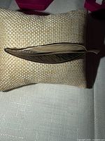 Front view of goldtone leaf brooch pin on display pillow