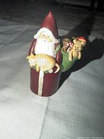 Front view of wooden Santa figurine showing cat and sack detail