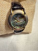 Front view of watch on cushion displaying abalone dial