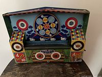 Front view of metal shooting gallery showing main target wheel, side targets, graphics