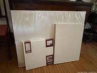 Front view of three shrink-wrapped blank canvases showing size comparison and Blick labels