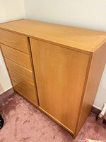 Front view of light oak dresser showing five drawers and cabinet door