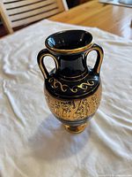 Front view of black ceramic amphora vase with gold decoration