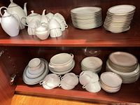 Cabinet shelves showing full dinnerware set including plates, bowls, cups and serving pieces
